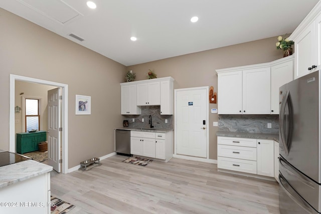 408 Third St, Saint Augustine, FL 32084 - kitchen featuring appliances with stainless steel finishes, decorative backsplash, white cabinets, light wood-type flooring, and light stone countertops