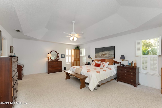 carpeted bedroom with a textured ceiling, a raised ceiling, and ceiling fan