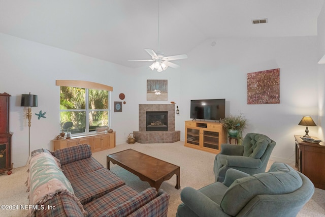 carpeted living room with a tile fireplace, ceiling fan, and vaulted ceiling