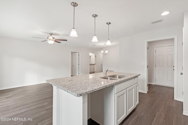 kitchen featuring sink, a kitchen island with sink, light stone counters, white cabinets, and decorative light fixtures