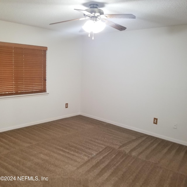 spare room featuring dark colored carpet and ceiling fan