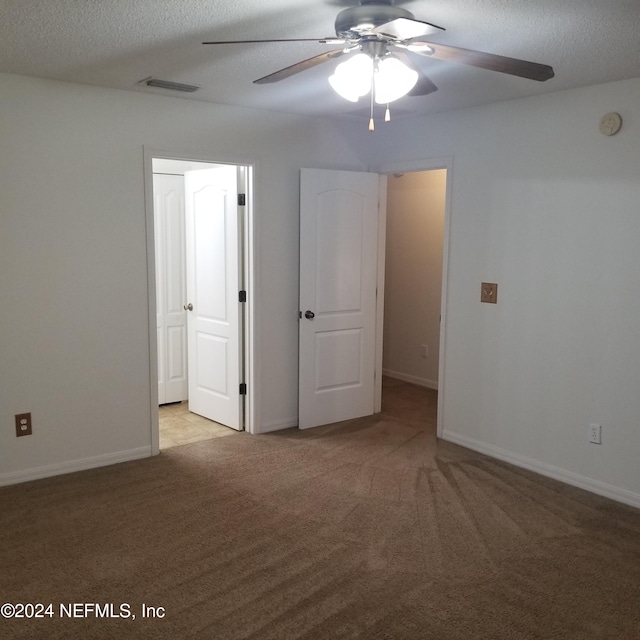 carpeted spare room with a textured ceiling and ceiling fan