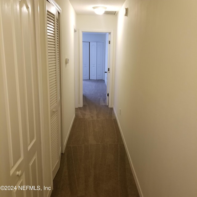 hallway featuring dark colored carpet