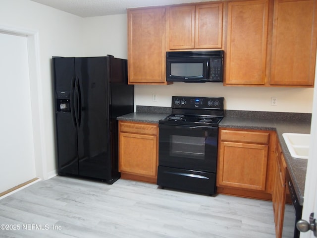 kitchen with black appliances, sink, and light hardwood / wood-style flooring