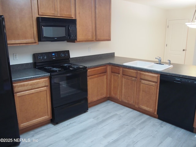 kitchen featuring black appliances, light wood-type flooring, and sink