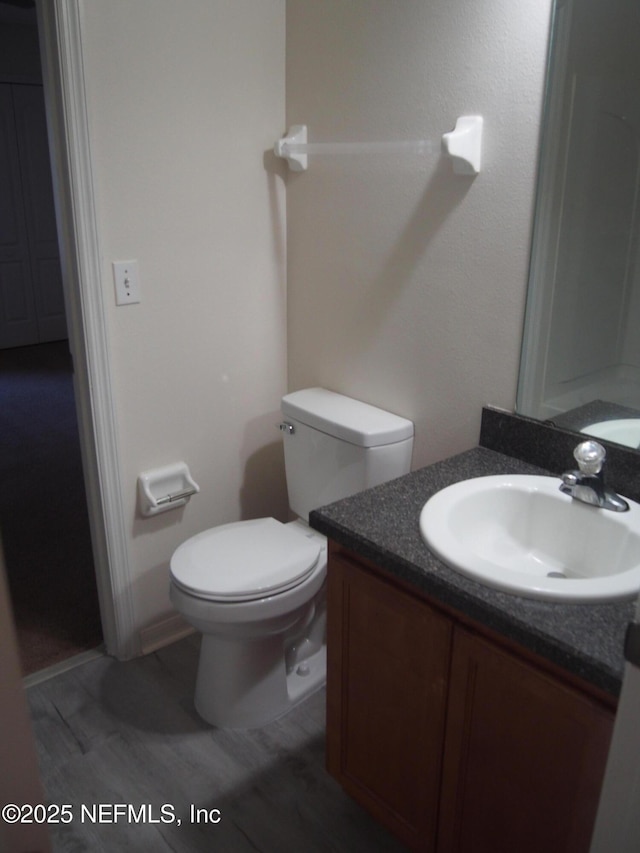 bathroom with hardwood / wood-style floors, toilet, and vanity