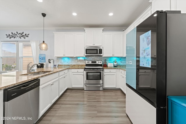 kitchen featuring appliances with stainless steel finishes, crown molding, sink, decorative light fixtures, and white cabinets