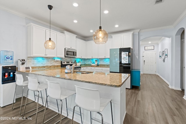 kitchen with kitchen peninsula, appliances with stainless steel finishes, light hardwood / wood-style flooring, white cabinetry, and hanging light fixtures