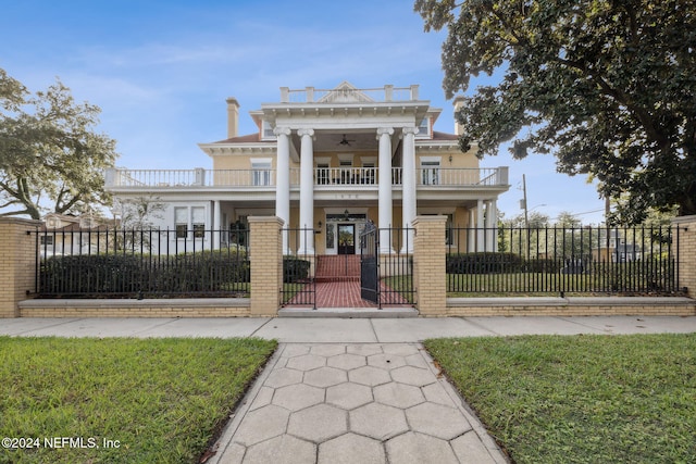 view of front facade with ceiling fan, a balcony, a front yard, and a porch