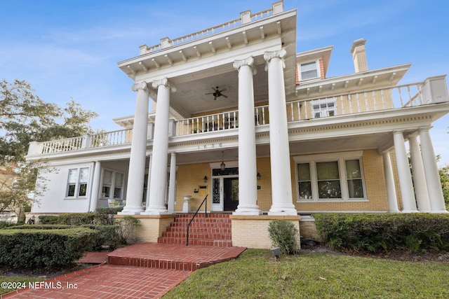 greek revival house featuring covered porch, ceiling fan, and a balcony