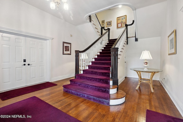 entryway with wood-type flooring and a towering ceiling