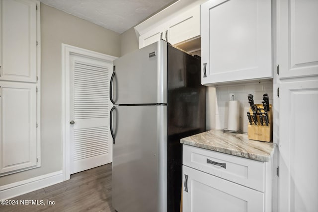 kitchen with stainless steel refrigerator, white cabinetry, tasteful backsplash, light stone countertops, and dark hardwood / wood-style flooring