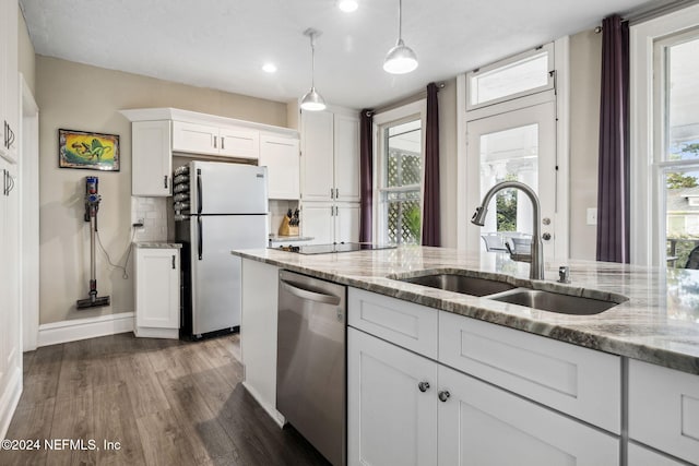 kitchen featuring white cabinetry, appliances with stainless steel finishes, light stone countertops, hanging light fixtures, and dark wood-type flooring