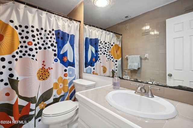 bathroom with curtained shower, vanity, and toilet