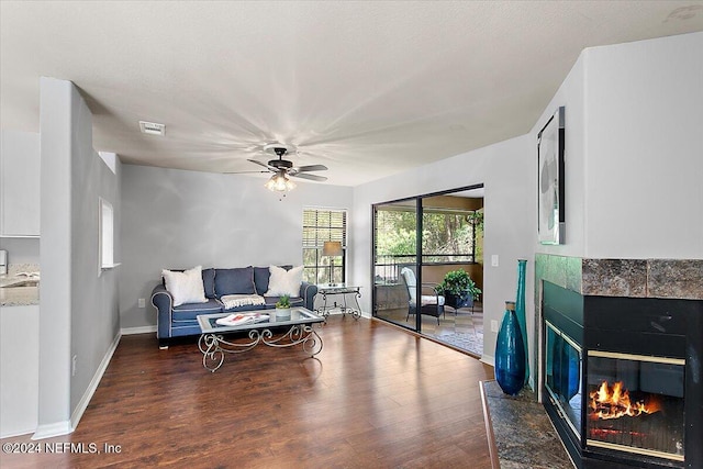 living area featuring a ceiling fan, a fireplace, visible vents, and dark wood-style flooring