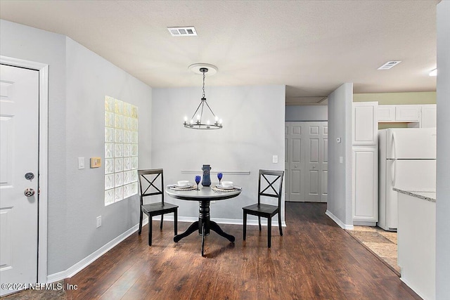 dining area with dark wood-style flooring, visible vents, a notable chandelier, and a textured ceiling