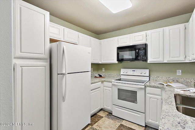 kitchen with light stone counters, stone finish flooring, white cabinets, a sink, and white appliances