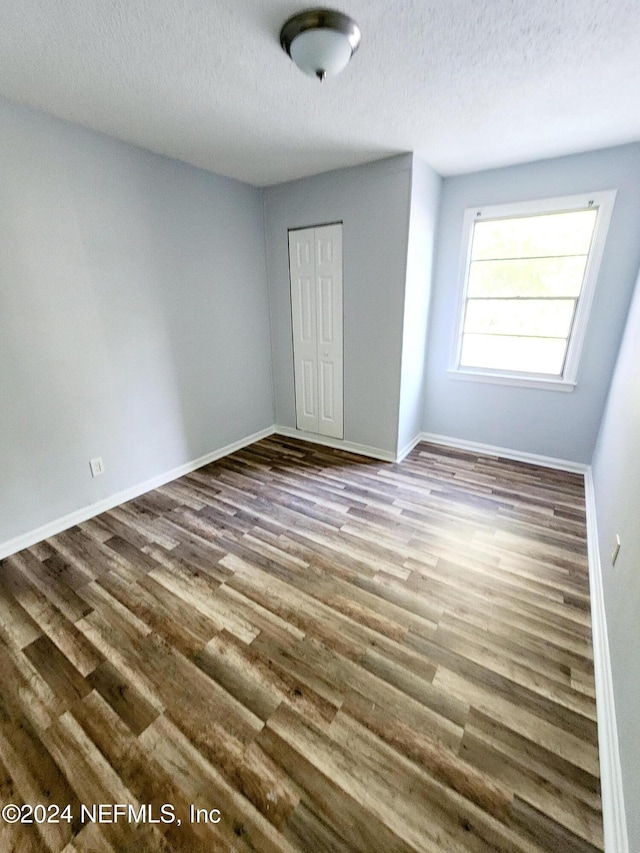 unfurnished bedroom with wood-type flooring, a textured ceiling, and a closet