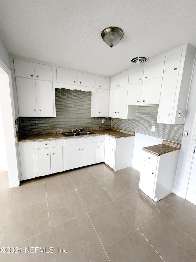 kitchen with tasteful backsplash, sink, and white cabinets