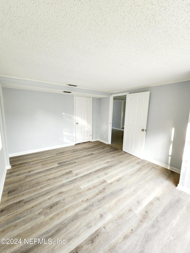 unfurnished bedroom featuring a textured ceiling, light hardwood / wood-style flooring, and a closet