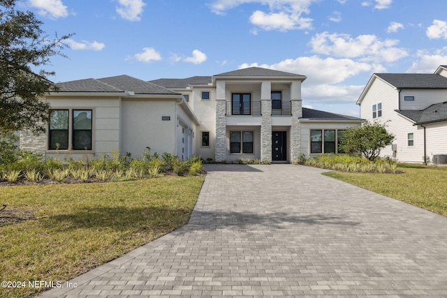 view of front of property with a balcony, central AC unit, and a front yard