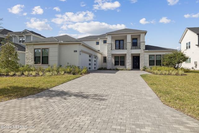 prairie-style house with a front yard, a balcony, and a garage