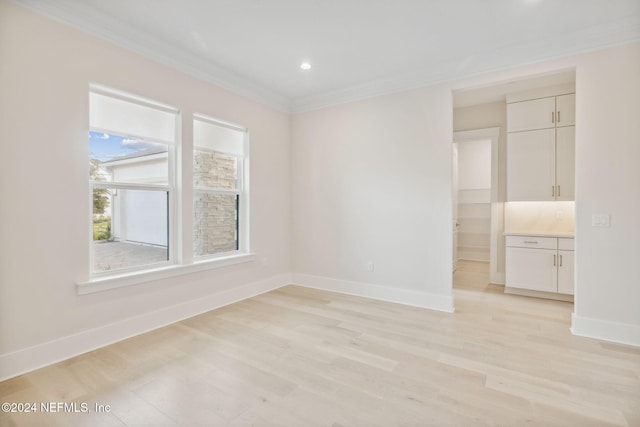 unfurnished room with light wood-type flooring and ornamental molding