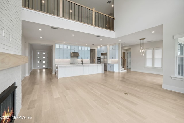 unfurnished living room featuring a high ceiling, light hardwood / wood-style flooring, and sink