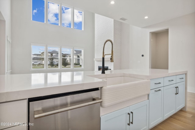 kitchen featuring dishwasher, white cabinets, light hardwood / wood-style floors, and sink