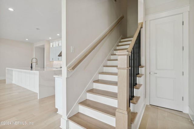 stairs featuring hardwood / wood-style flooring and sink