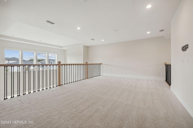 spare room featuring a tray ceiling and light colored carpet