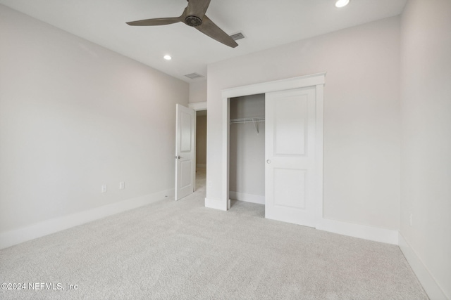 unfurnished bedroom featuring ceiling fan, light colored carpet, and a closet