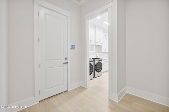 washroom with washer and dryer, light hardwood / wood-style flooring, and cabinets