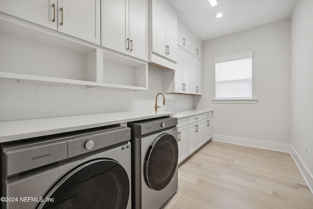 washroom featuring cabinets, washing machine and dryer, light hardwood / wood-style flooring, and sink