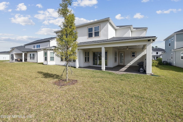 rear view of property with ceiling fan, a patio area, and a yard