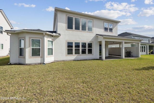 back of property with a lawn and a patio