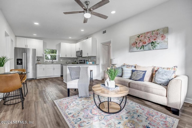 living room with ceiling fan, sink, and dark wood-type flooring