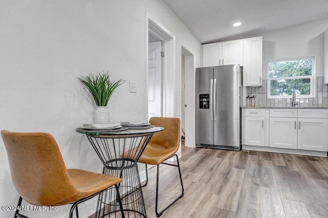 kitchen featuring white cabinets, light stone countertops, stainless steel fridge with ice dispenser, and sink