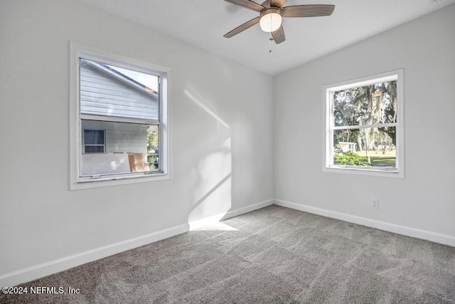 carpeted empty room featuring ceiling fan and a wealth of natural light