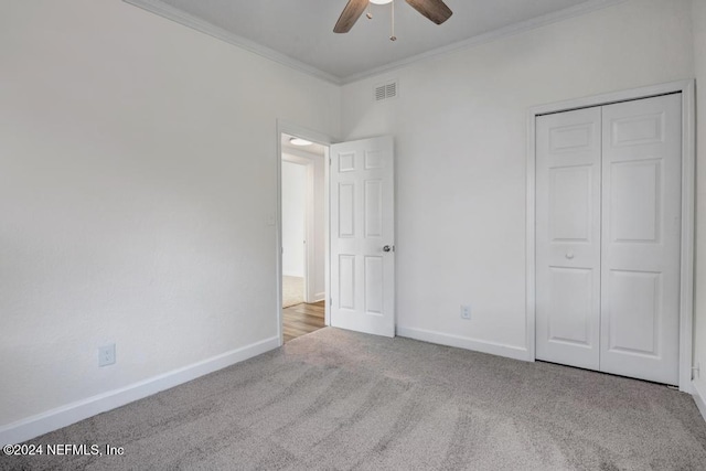 unfurnished bedroom featuring ceiling fan, light colored carpet, ornamental molding, and a closet