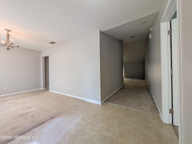 empty room featuring a notable chandelier and a textured ceiling