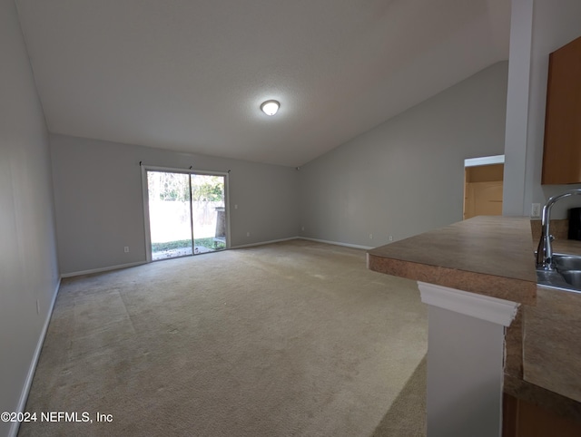 unfurnished living room featuring light colored carpet, sink, and vaulted ceiling