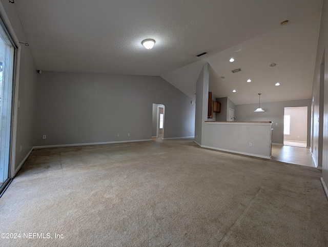 unfurnished living room with a textured ceiling, light carpet, and vaulted ceiling