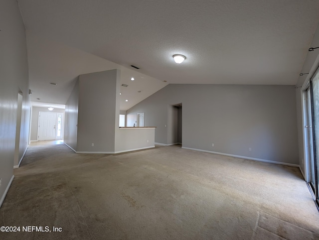 interior space with a textured ceiling, light colored carpet, and lofted ceiling