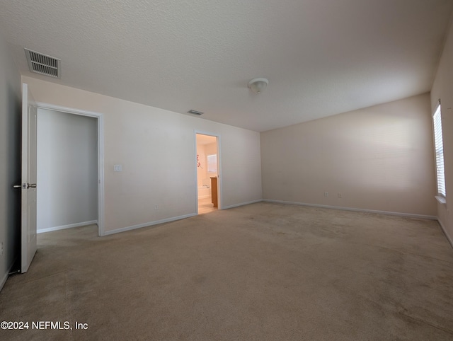 unfurnished room featuring a textured ceiling and light colored carpet