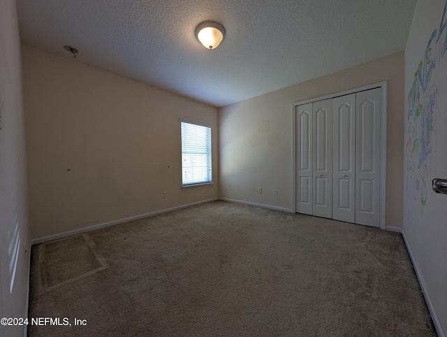 unfurnished bedroom featuring carpet flooring, a textured ceiling, and a closet