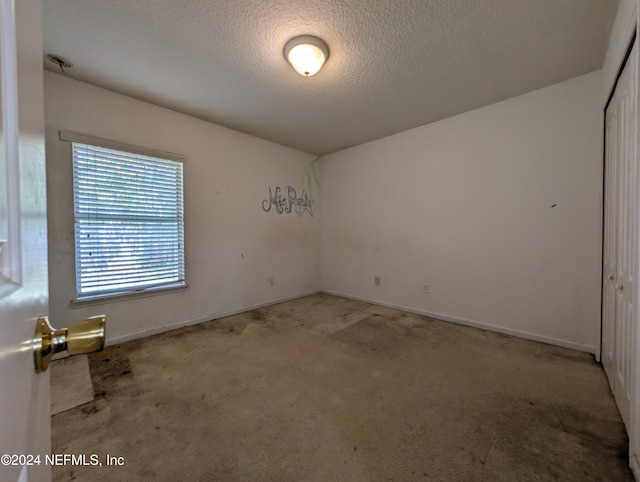 carpeted spare room with a textured ceiling