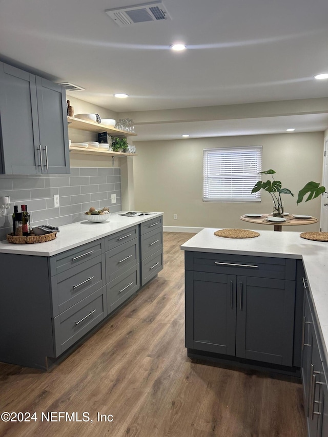 kitchen with gray cabinets, dark hardwood / wood-style floors, and backsplash