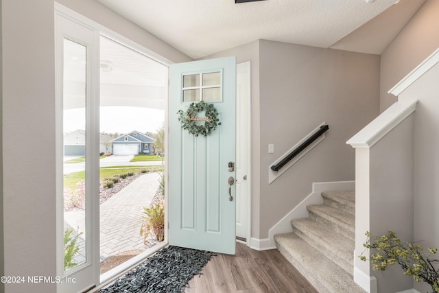 entrance foyer with a textured ceiling, hardwood / wood-style flooring, and vaulted ceiling