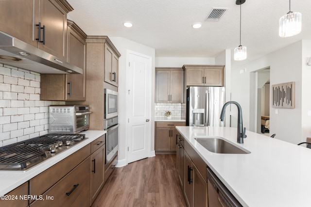 kitchen with stainless steel appliances, hanging light fixtures, decorative backsplash, sink, and dark wood-type flooring